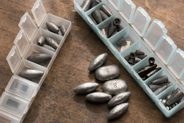 lead weights sinkers in plastic containers, on a surface